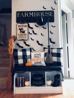 a black and white halloween themed entryway with bats on the wall, witch pillows, brooms, and other decorations