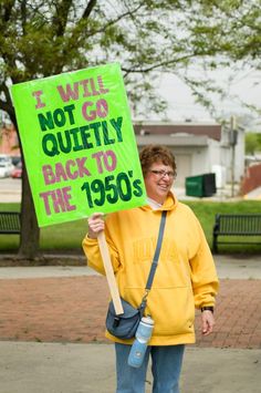 a person holding a sign that says we will not go quietly back to the 1950's