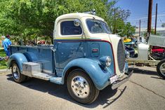 an old blue and white truck parked on the street