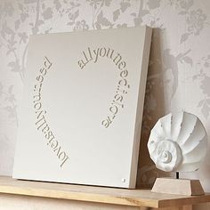 a white box sitting on top of a wooden shelf next to a vase and wallpaper