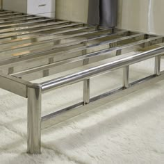 a metal bed frame sitting on top of a white carpeted floor next to a wall