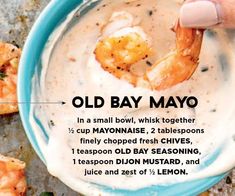 a hand dipping shrimp into a bowl of old bay mayo