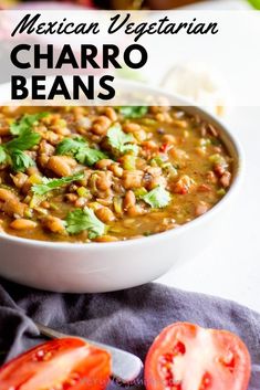 mexican vegetarian charro beans in a white bowl with tomatoes and cilantro on the side