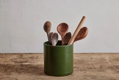 several wooden spoons in a green cup on a table