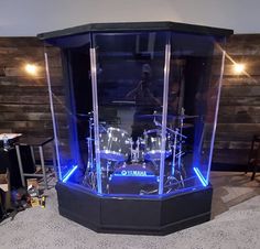 a drum set in a glass case with blue lights