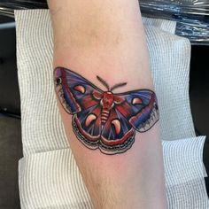 a colorful butterfly tattoo on the left arm and leg, it looks like an insect