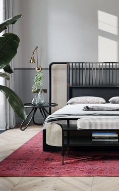 a bed sitting on top of a wooden floor next to a plant in a room