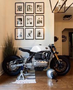 a motorcycle is parked in the middle of a room with pictures on the wall behind it