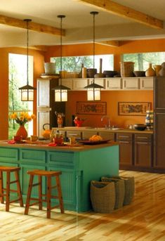 a kitchen with wooden floors and an island in front of the stove top oven is painted teal