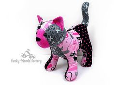 a pink and black cat stuffed animal with polka dots on it's chest, standing upright