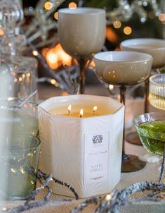 candles and dishes on a table with christmas lights in the background