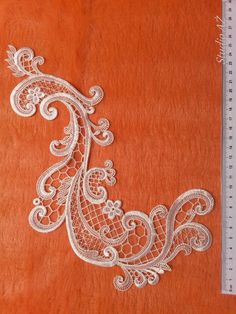 an orange piece of cloth with white lace on it and a ruler next to it