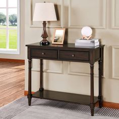 a wooden table with two drawers and a lamp on it in front of a window