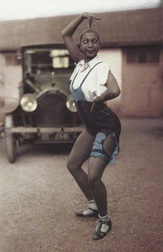 an old photo of a woman standing in front of a car with her arms up