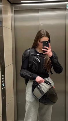 a woman taking a selfie in an elevator with her helmet on and holding a cell phone