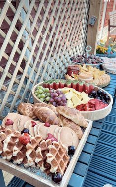 several trays of different types of food on a blue table with wooden slats