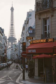 the eiffel tower is in the background of this street scene with cars and people