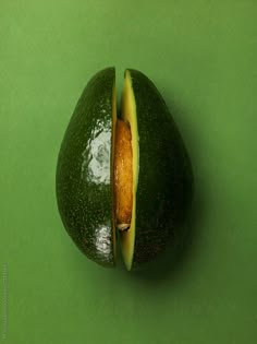 an avocado cut in half on a green surface