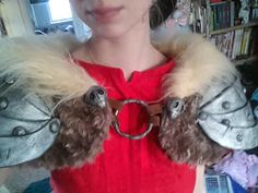 a woman in a red shirt is holding two stuffed animals on her hands and wearing handcuffs