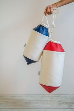 two white and blue bags hanging from the side of a wall with one bag attached to it