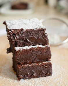 three pieces of chocolate cake sitting on top of a wooden table