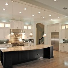 a large kitchen with white cabinets and black island in the center, along with stainless steel appliances