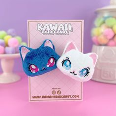 two blue and white cat hair clips sitting on top of a pink table next to candy