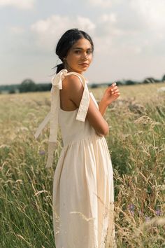 a woman in a dress standing in tall grass