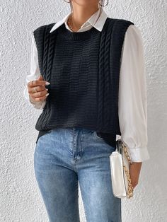 a woman wearing a black sweater vest and jeans holding a white purse in her right hand