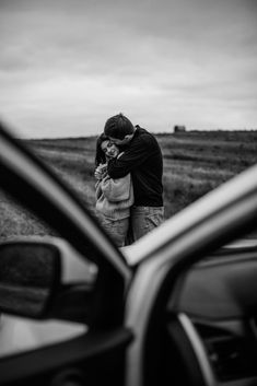 a man and woman standing next to each other in front of a car