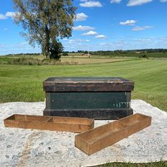 an old trunk sitting on top of a rock in the middle of a field next to another box