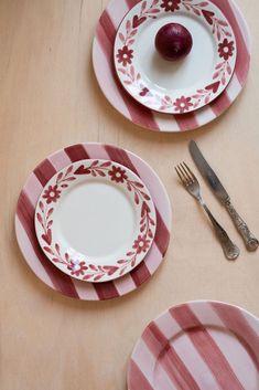 three plates with red and white designs on them, one has an apple in the middle