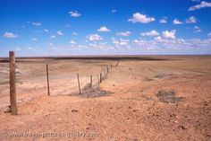 a dirt field with a wooden fence in the middle