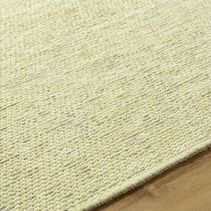 a close up view of the textured area rug on top of a wooden floor