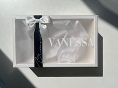 a white box with a black tie and the word vanessa written on it