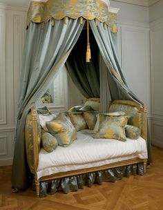 the canopy bed is decorated with gold and green pillows