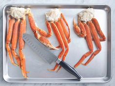 crab legs are being cut up on a tray with a large knife in the middle