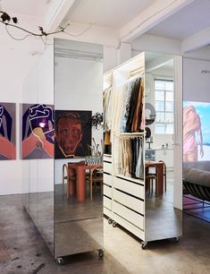 a mirrored closet with clothes hanging on it's sides and paintings in the background