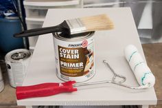 a paint can with a brush and some other items on it next to a roller