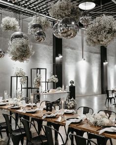 the tables are set with white flowers and silver balls hanging from the ceiling above them