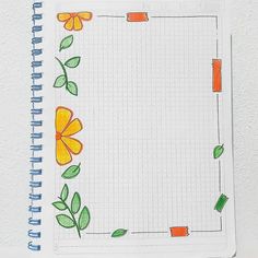 a notebook with an orange flower and green leaves drawn on it, sitting on top of a white surface