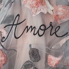 an embroidered dress with flowers and the word'amore'written in black on it