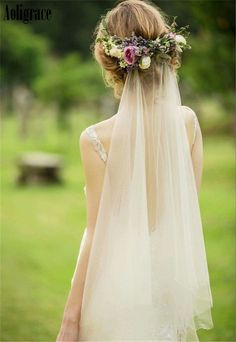 a woman wearing a veil and flowers in her hair is looking at the grass outside