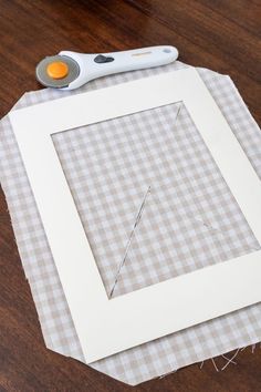 a pair of scissors sitting on top of a piece of paper next to a square