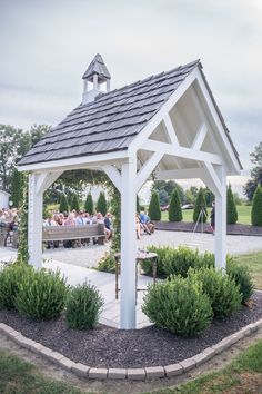 a white gazebo sitting in the middle of a park with people eating and drinking