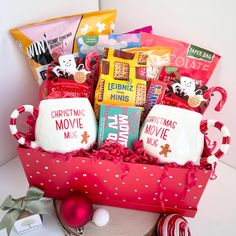 a red box filled with lots of different types of snacks and candys next to a christmas ornament