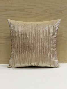 a white and gold pillow sitting on top of a wooden floor next to a wall