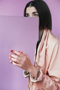 a woman holding up a square piece of paper with her face in the middle of it