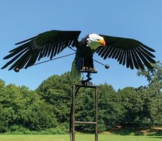 a large bird sitting on top of a metal object in the middle of a field