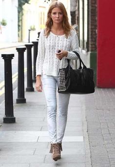 a woman is walking down the street with a handbag and cell phone in her hand